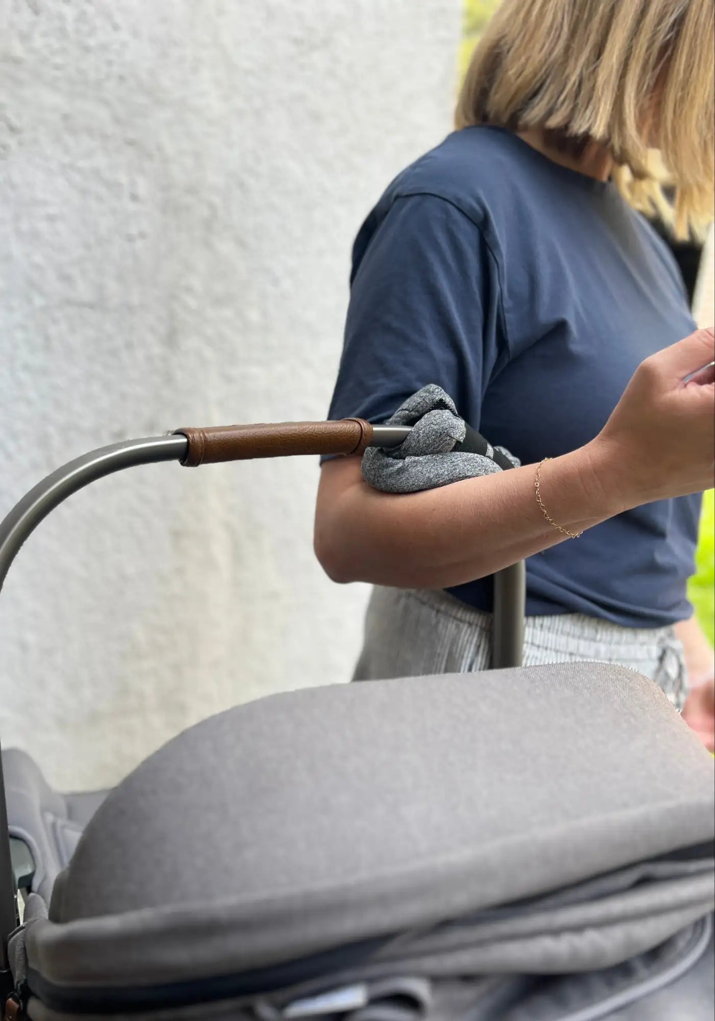 Grey stroller with brown leather accents and wooden handlebars.